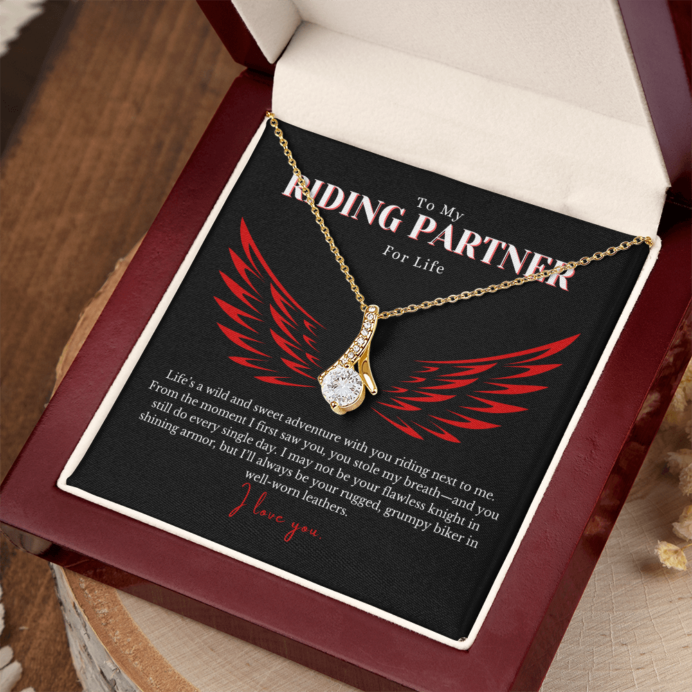 Elegant Alluring Beauty Necklace featuring a 7mm cubic zirconia stone set in a petite ribbon-shaped pendant with a 14k white gold or 18k yellow gold finish over stainless steel. A romantic gift for a biker’s wife, complete with a heartfelt love message. Comes in a gift-ready box with an optional mahogany luxury box featuring an LED light for an unforgettable presentation.