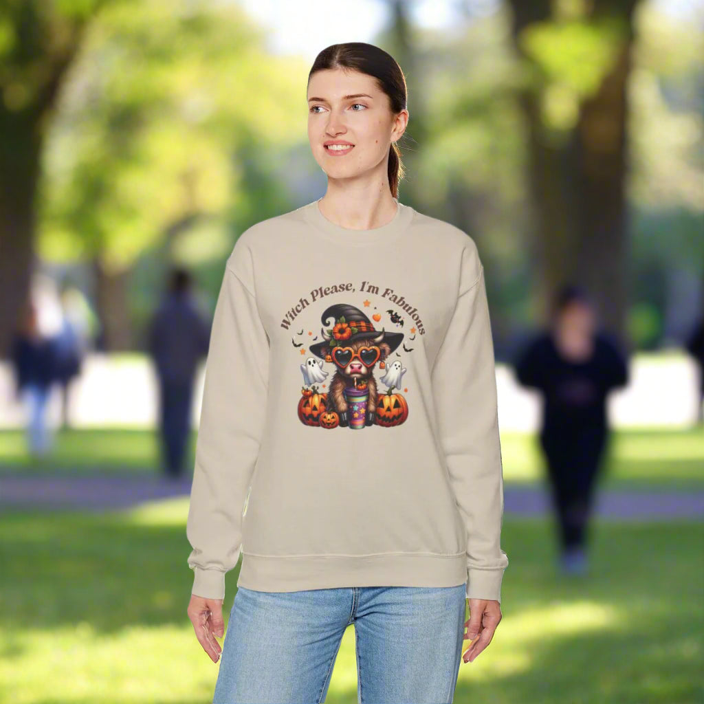 Woman wearing a light tan crewneck sweatshirt with "Witch Please, I'm Fabulous" text and Halloween-themed graphic featuring a cute witch character with hat, glasses, and colorful outfit surrounded by jack-o'-lanterns, ghosts, and autumn leaves