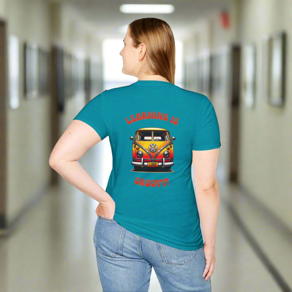 Back view of a woman wearing a teal T-shirt in a school hallway, featuring a retro VW bus and the phrase “Learning Is Groovy.” Customizable with a teacher’s name.