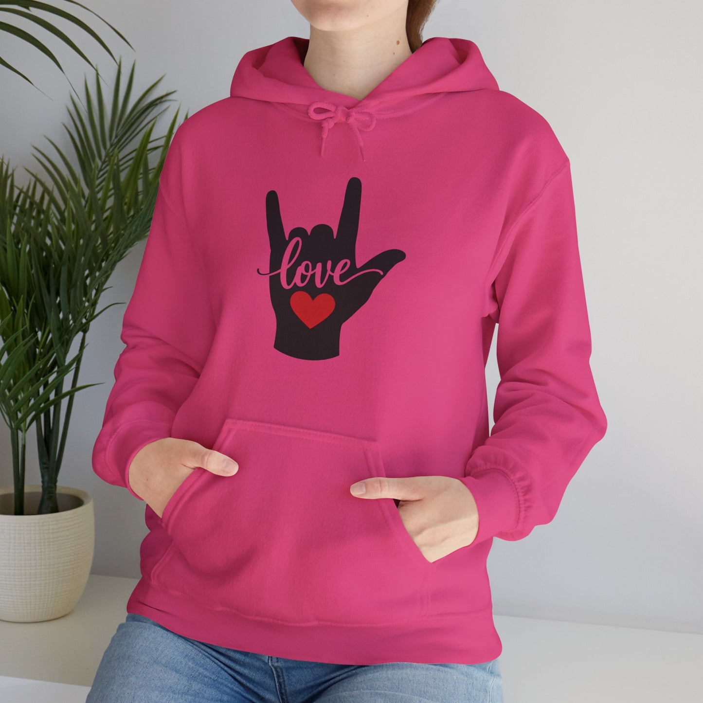 Hot pink hoodie featuring black hand silhouette making the ASL sign for "I love you" with the word "love" written across the fingers and a small red heart in the palm