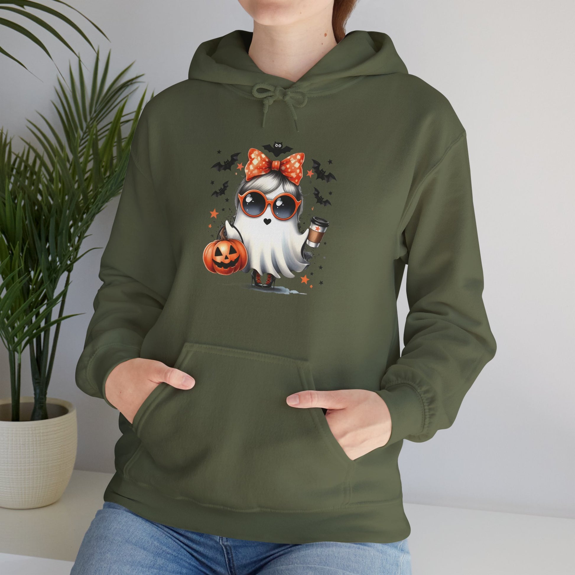 "Olive green unisex hoodie featuring cute cartoon ghost character wearing orange polka-dot bow and sunglasses, holding coffee cup and Halloween pumpkin, surrounded by flying bats and stars - Halloween coffee lover sweatshirt"