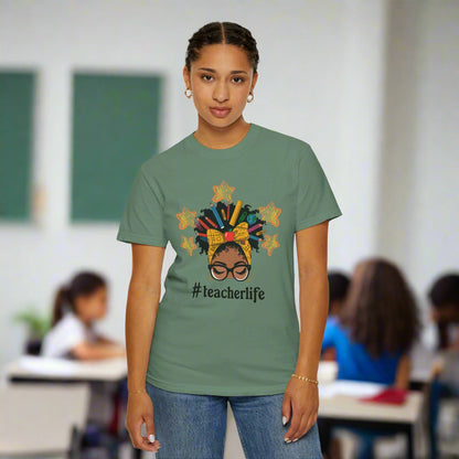 Illustration of an Afrocentric woman with glasses and a headwrap filled with school supplies, surrounded by yellow stars – featured on a unisex garment-dyed teacher T-shirt celebrating education and individuality.