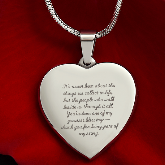 Engraved heart necklace with sentimental message on polished stainless steel pendant displayed on red background, adjustable snake chain, customizable jewelry gift for loved ones.