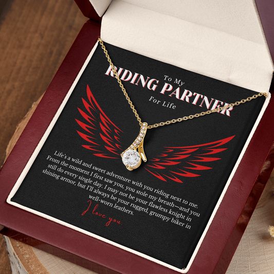 Elegant Alluring Beauty Necklace featuring a 7mm cubic zirconia stone set in a petite ribbon-shaped pendant with a 14k white gold or 18k yellow gold finish over stainless steel. A romantic gift for a biker’s wife, complete with a heartfelt love message. Comes in a gift-ready box with an optional mahogany luxury box featuring an LED light for an unforgettable presentation.