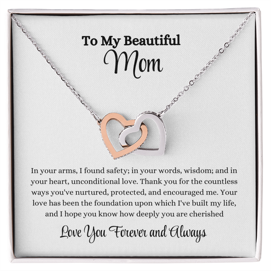 Interlocking Hearts Necklace in rose gold and yellow gold with sparkling CZ crystals, displayed with heartfelt message card: "In your arms, I found safety..." – perfect gift for mom, wife, or daughter