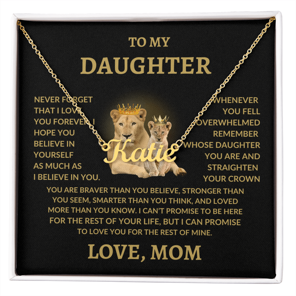 Personalized name necklace with the name "Katie" in gold, displayed on a heartfelt message card from mom to daughter featuring a lioness and her cub with crowns. The necklace rests on a black background inside a gift box with a touching message in gold text.