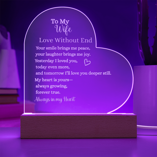 Heart-shaped engraved acrylic plaque with LED wooden base, glowing purple light, featuring romantic “To My Wife – Love Without End” message about everlasting love.
