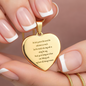 Gold engraved heart pendant necklace held in hand showing French manicure, personalized jewelry with romantic message engraved on polished 18K yellow gold finish heart charm attached to snake chain
