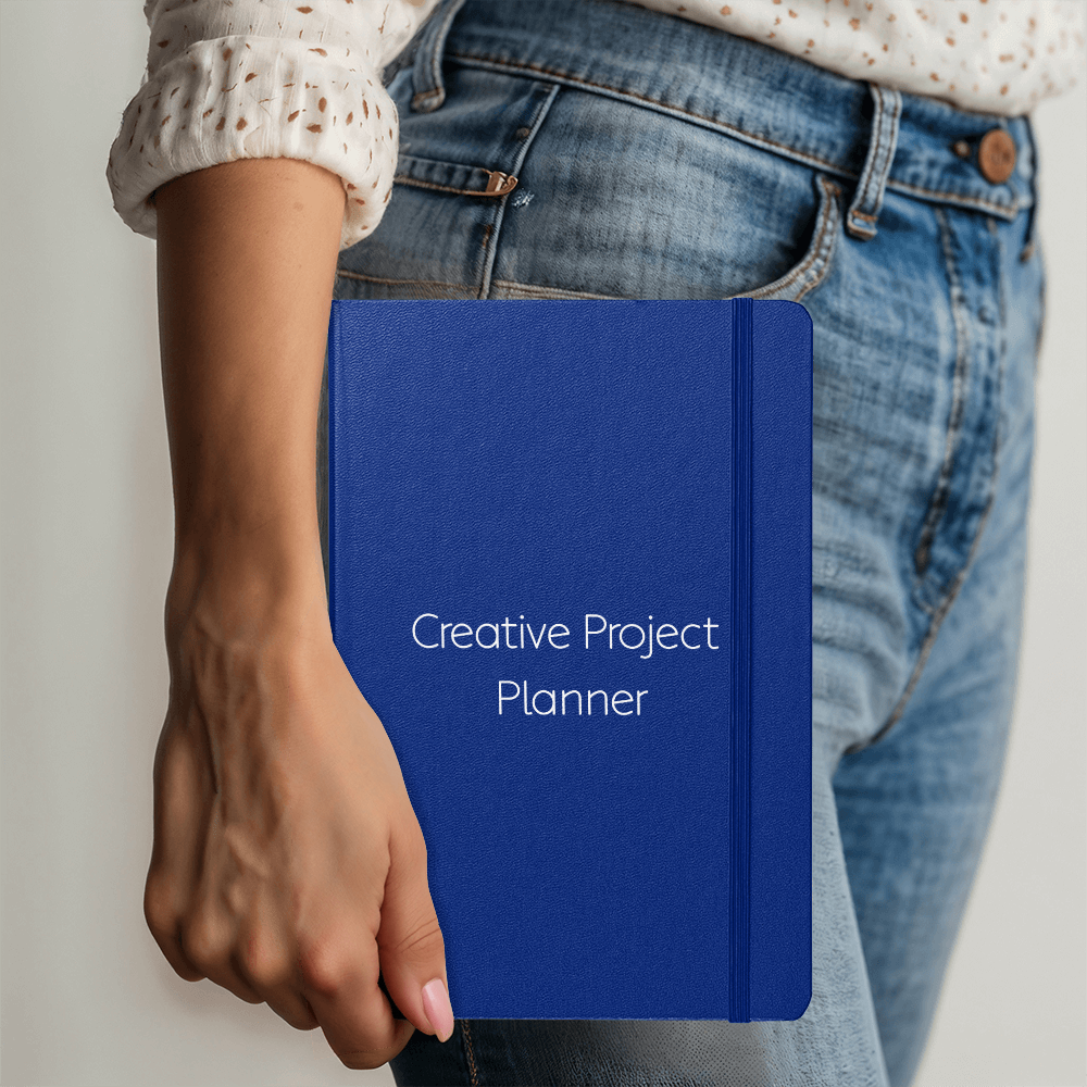 Navy blue hardcover creative project planner journal with white text and elastic closure on white background, featuring ribbon bookmark for professional project management and creative planning
