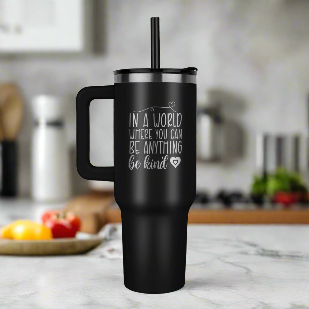 Black 40oz insulated stainless steel tumbler with handle and straw, laser-engraved with the phrase “In a world where you can be anything, be kind” – inspirational hot and cold travel mug