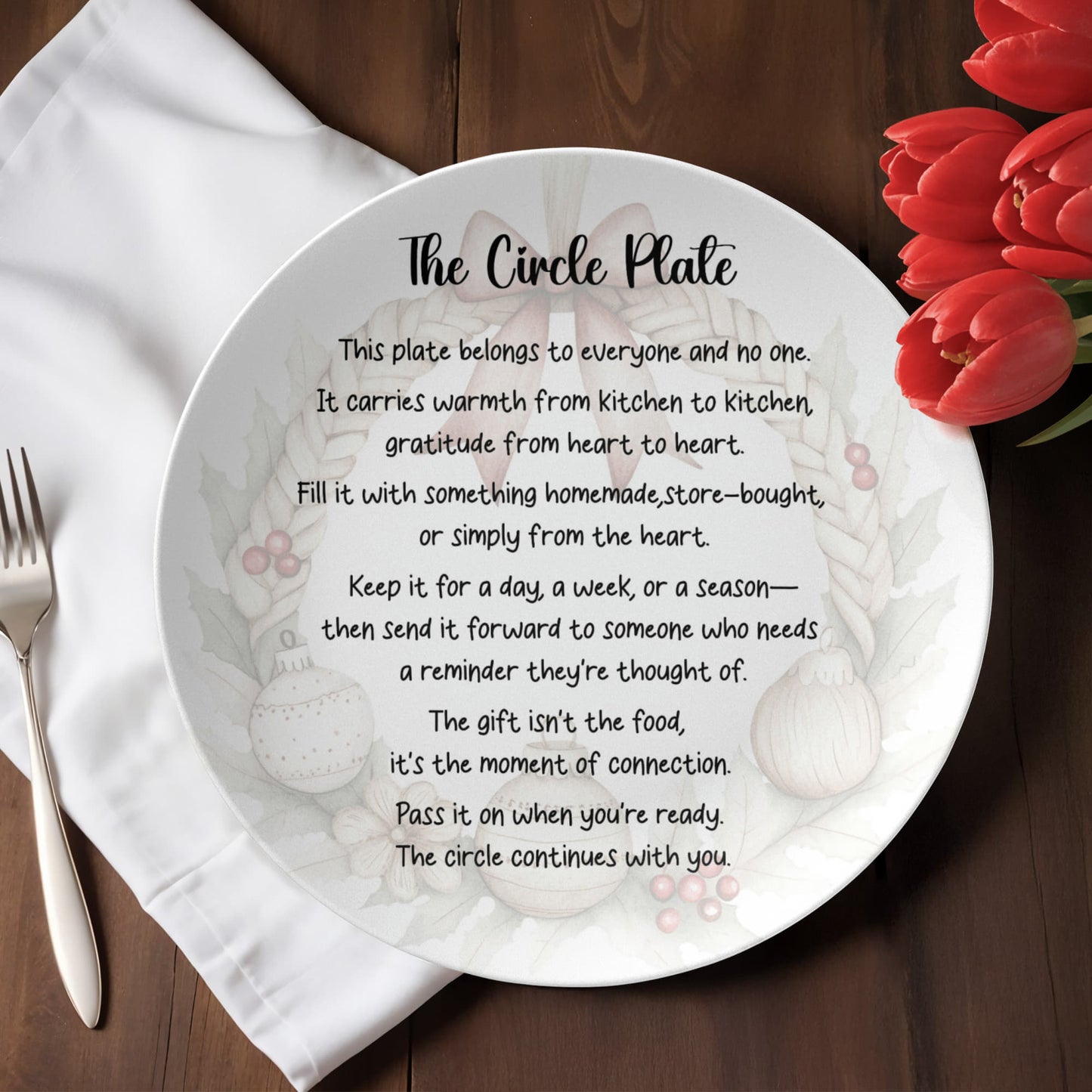 The Circle Plate - white 10 inch ceramic dinner plate with farmhouse wreath design and text "This plate belongs to everyone and no one, pass it on when you're ready, the circle continues with you" on rustic wood table setting with flowers