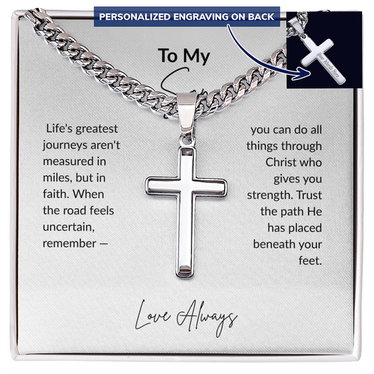 Personalized men's cross necklace with Cuban link chain displayed on a silver gift box with faith-inspired message reading "Life's greatest journeys aren't measured in miles, but in faith" — available in 18K gold or polished stainless steel with custom back engraving. Perfect Christian gift for son, husband, or graduation.