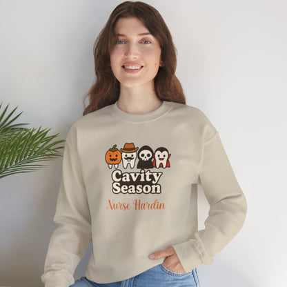Woman wearing a beige Halloween-themed sweatshirt that says "Cavity Season" with four cute tooth characters in costumes (pumpkin, cowboy, skull, and vampire) and personalized with the name "Nurse Hardin."