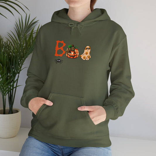 Person wearing an olive green Halloween hoodie with the word “BOO” spelled out using a pumpkin jack-o’-lantern, a ghost, and a spider design.